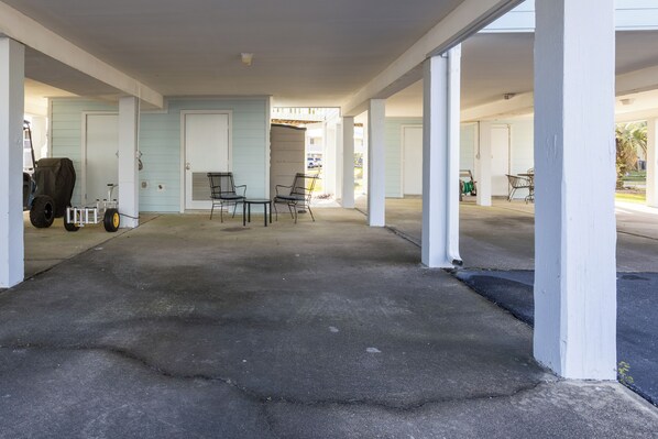 A covered outdoor area with a concrete floor, white pillars, and a table with chairs.