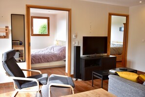 Een moderne kamer met een bed, een televisie, een bank, een stoel en een kleine tafel.