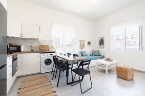 Une cuisine compacte comprenant un coin repas, un lave-linge et un canapé.