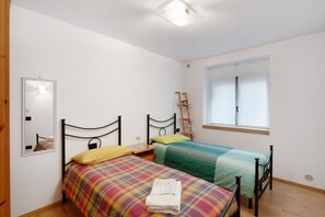 Un dormitorio con dos camas, una ventana, un espejo y suelo de madera.