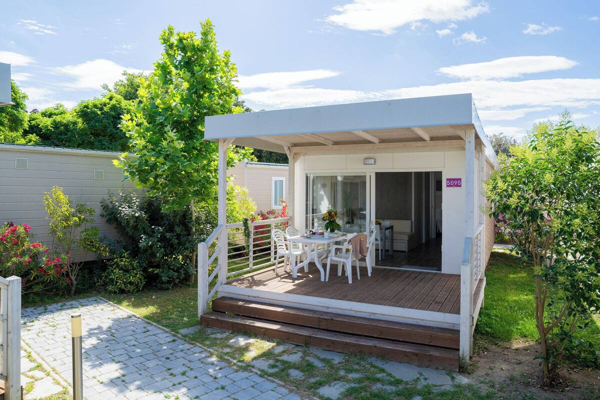A small, single-story structure with a covered patio, a table with chairs, and a door marked with the number 5095.