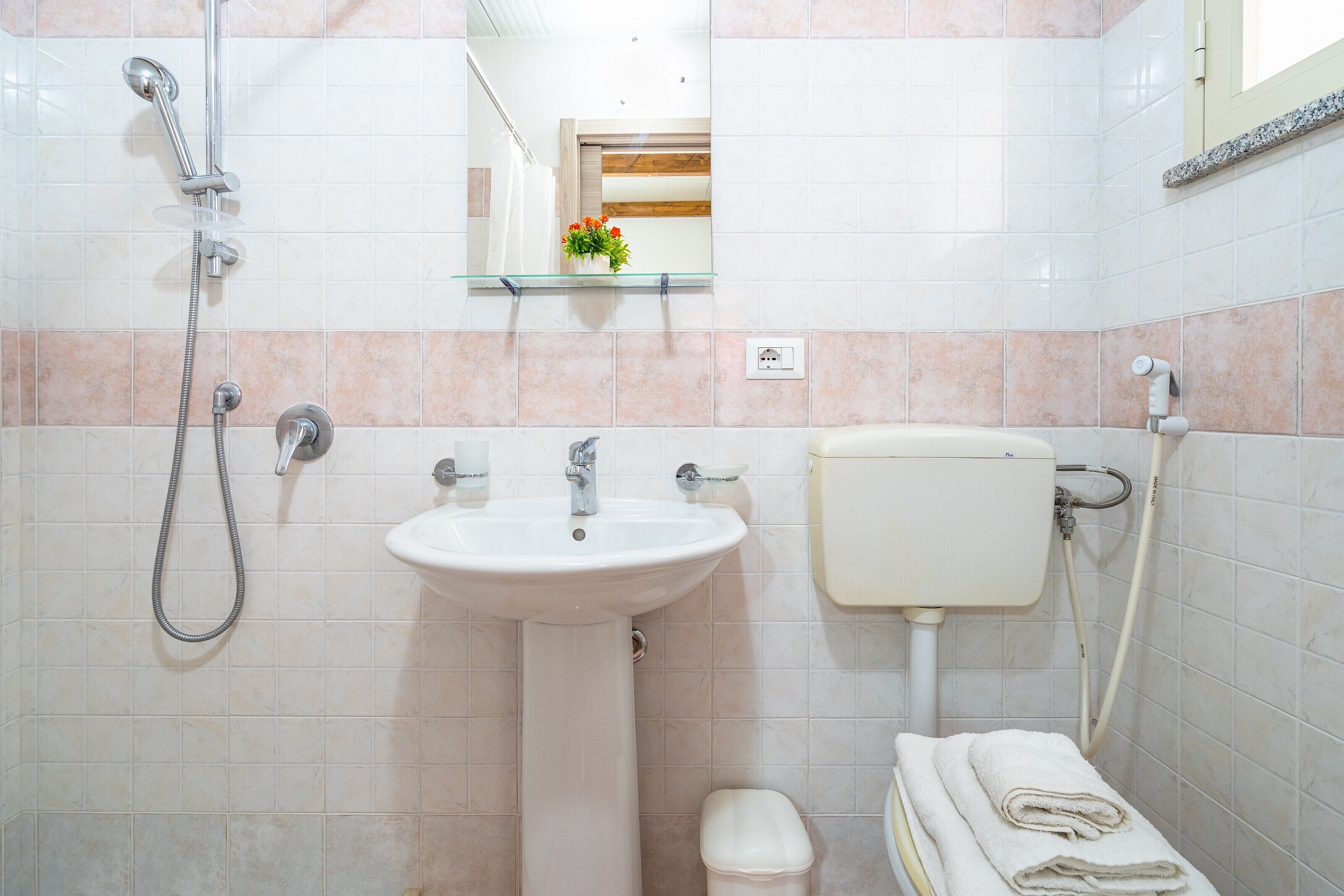 A bathroom with a sink, toilet, shower, and a mirror above the sink.