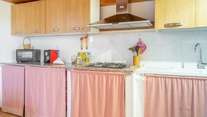 A kitchen with wooden cabinets, a gas stove, a toaster, and a sink. - Apartment 'Nonna Rosa' with Private Terrace, Shared Garden and Air Conditioning (Pachino)