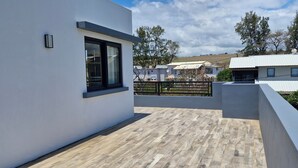 A modern building with a flat roof, a large window, and a wooden deck.