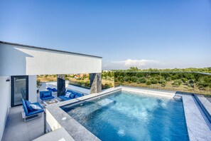 A modern outdoor pool area with blue lounge chairs and a clear view of the surrounding landscape. - Villa Elena Zadarvillas (Nin)