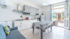 A modern kitchen with a dining area, a washing machine, and a view of the outdoors. - Villa 'Con Tre Camere Da Letto' with Private Terrace, Shared Garden and Air Conditioning (Pachino)
