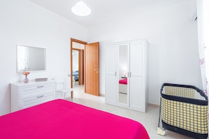 A bedroom with a bed, a dresser, a wardrobe, and a crib.