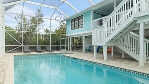A pool area with a covered deck, a staircase, and outdoor seating.