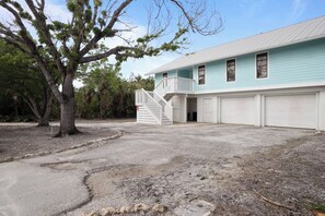 A two-story house with a front porch, a staircase, and a garage. - Aside The Sea | Pet Friendly, Steps to the beach, 3 bedroom 2 bath with pool! (Sanibel)