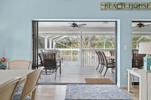 A beach house interior with a dining area, a ceiling fan, and a view of the outdoors. - Aside The Sea | Pet Friendly, Steps to the beach, 3 bedroom 2 bath with pool! (Sanibel)