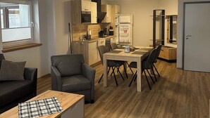 A modern, compact living space with a kitchenette, dining area, and seating.
