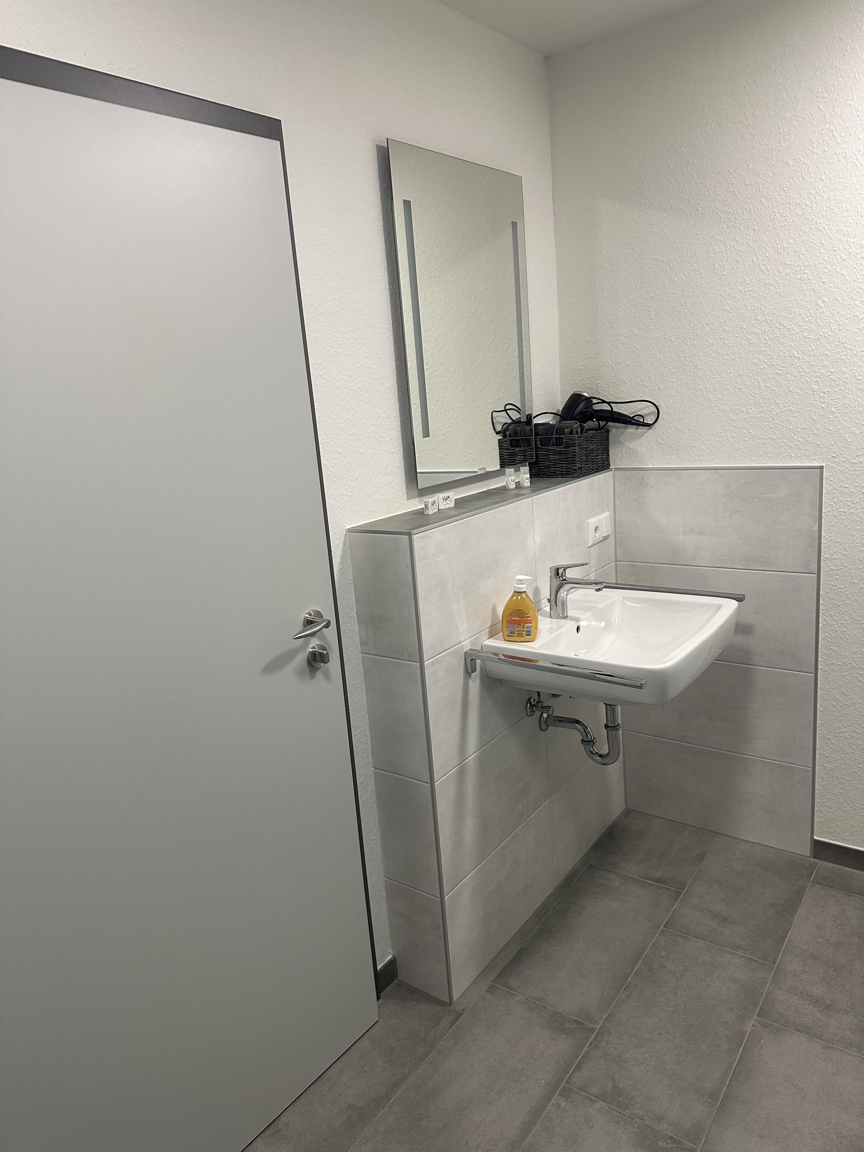 A bathroom with a white sink, a mirror, and a door.