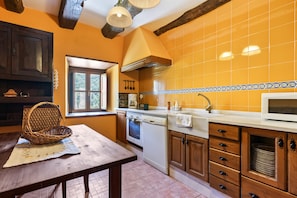 Una cocina con una mesa de madera, un microondas y una ventana.