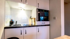 A modern kitchen with white cabinets, a black countertop, and a built-in oven. - 7 Domus House Studio Apartment -  a studio that sleeps 2 guests  in 1 bedroom (Chester)