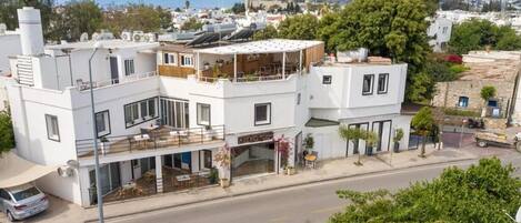 Un edificio blanco con un restaurante en la planta baja, un balcón y vistas a la calle y al paisaje urbano.