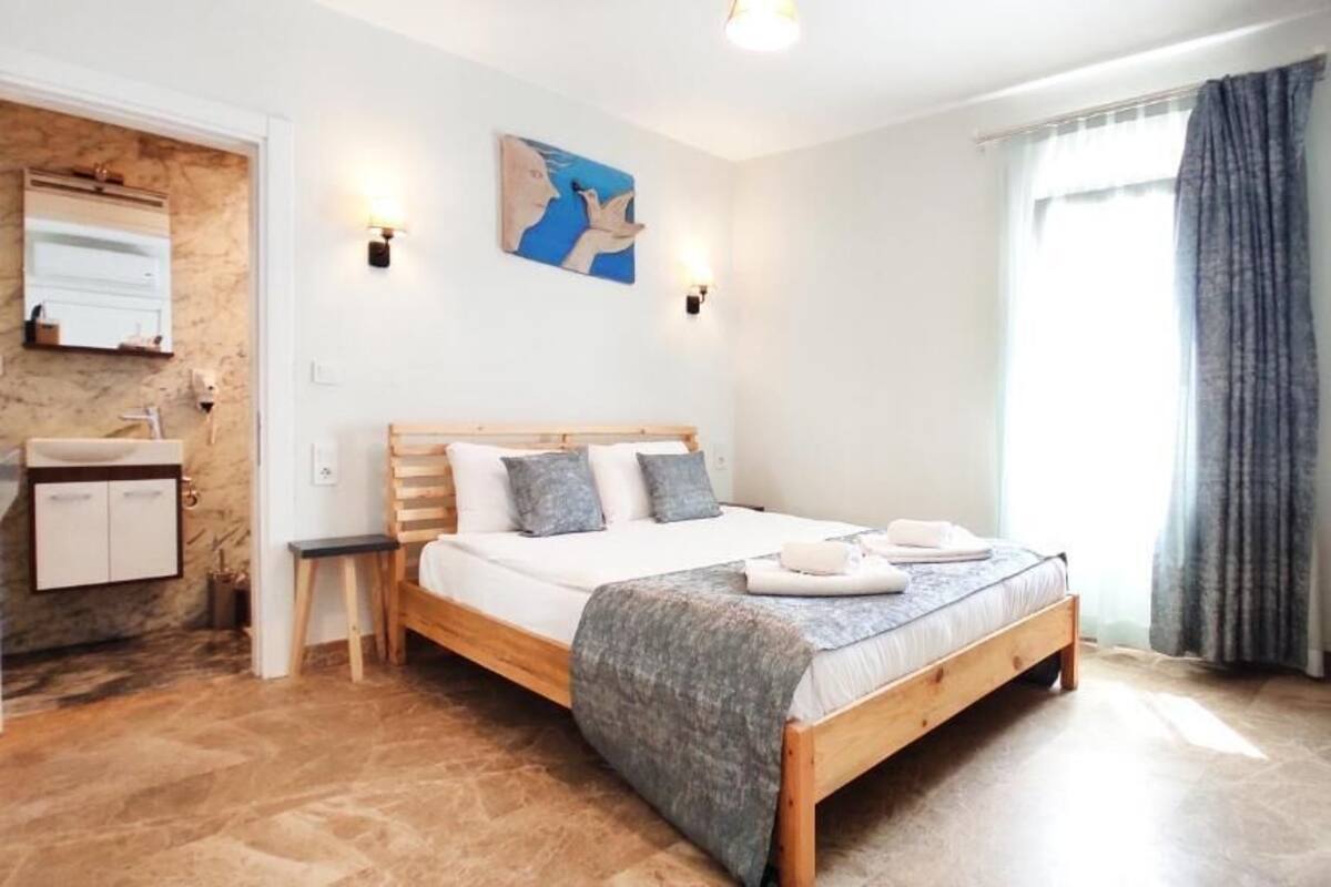 Ein Schlafzimmer mit einem hölzernen Bett, einem Nachttisch, einem Spiegel, einem Gemälde, einem Kleiderschrank und einem Fenster mit Vorhängen.
