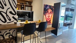 A modern kitchen with a dining area, a large painting, and a TV.