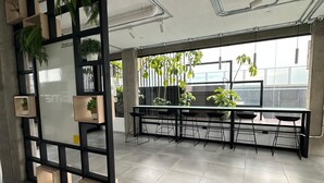 A modern indoor space with a black and white bookshelf, tiled flooring, and a view of greenery outside.