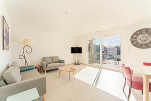 Un soggiorno moderno con un divano, un tavolino, una TV e una zona pranzo con sedie.