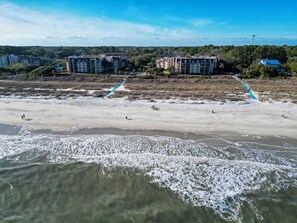 A beach with a clear view of a multi-story building in the background. - Sunset Rentals | Island Club 5502 (Hilton Head Island)