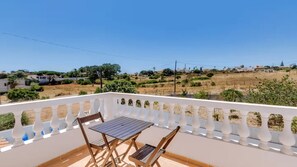 Ein Balkon mit Tisch und Stühlen, der einen Wohnbereich mit Häusern und Grünflächen blickt.