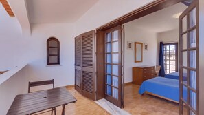Um quarto com uma cama, cômoda, cadeira e mesa.