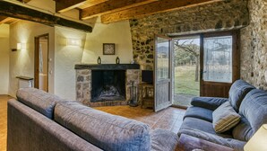 A cozy living room with a stone fireplace, a sofa, and a television.