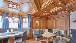 L'interno accogliente di una baita con soffitto in legno, zona pranzo, divano e tappeto in pelle di vacca.