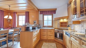 Una cucina con mobili in legno, forno a incasso, lavello e zona pranzo con tavolo e sedie.