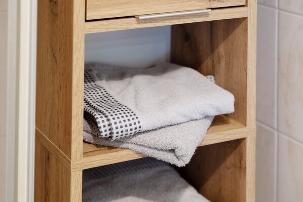 Un mueble de madera con una toalla y un paño estampado en su interior.