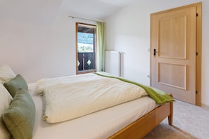 Een slaapkamer met een bed, een radiator, een deur en een raam.