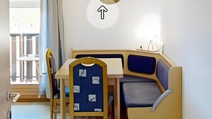 Uma área de refeições com mesa, cadeiras e um banco embutido.