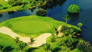 A golf course with sand bunkers, water hazards, and palm trees. - GLOBALSTAY Cocotal Condo in Punta Cana (Punta Cana)