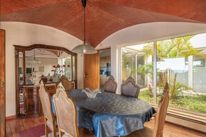 A dining area with a table, chairs, and a view of a garden through large windows. - Villa 'Andrea' with Private Pool, Wi-Fi and Air Conditioning (Albufeira)