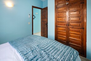 A bedroom with a bed, a wooden wardrobe, and a light switch on the wall. - Apartment 'Sea View Capistrano Village' with Sea View, Wi-Fi and Air Conditioning (Nerja)