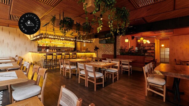 A restaurant with wooden tables and chairs, a bar area with bottles, and hanging plants. - Modern 2BD apt near Provenza and Parque Lleras (Medellín)