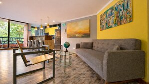 A modern living room with a grey sofa, a glass coffee table, and a painting on the wall. - Modern 2BD apt near Provenza and Parque Lleras (Medellín)