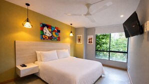 A bedroom with a bed, a nightstand, a ceiling fan, a TV, and a window with a view of greenery. - Modern 2BD apt near Provenza and Parque Lleras (Medellín)
