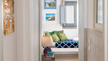 A room with a bed, a lamp, and two paintings on the wall.