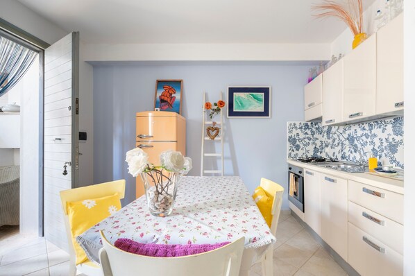 Une cuisine avec une table à manger, des chaises, un vase de fleurs, une échelle et une cuisinière.