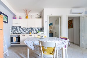 Une cuisine avec des meubles blancs, une cuisinière et une table à manger avec des chaises.