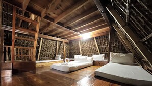 A cozy attic bedroom with wooden beams, a sloped ceiling, and a bed with white linens. - Sagada Heritage Village (Sagada)