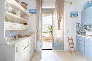Una cocina con armarios blancos, una escalera de madera y vista a un patio exterior.