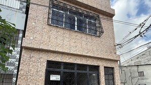 Een meerlaags gebouw met een garagebord, een zwart hek en een auto voor de deur.
