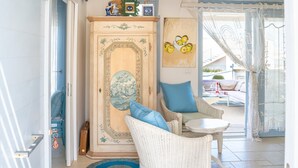 Quarto com guarda-roupa de madeira, móveis de vime, uma mesinha e vista para o exterior.