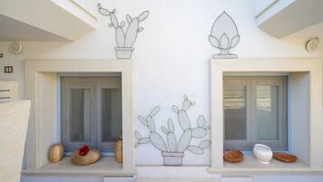 A building facade with two windows, each with a potted cactus decoration.