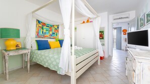A bedroom with a four-poster bed, a television, a bedside table with a lamp, and a colorful abstract painting on the wall. - Holiday Home 'Le Terrazze Otranto 2' with Shared Terrace, Wi-Fi and Air Conditioning (Otranto)