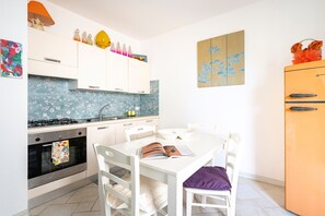 Una cocina moderna con armarios blancos, una estufa a gas, un horno y una mesa de comedor con sillas.