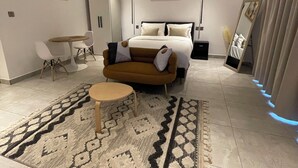 Un dormitorio moderno con una cama, un sofá, una mesa de comedor y un espejo grande.