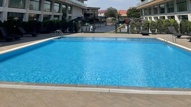 Una piscina rodeada de edificios de apartamentos modernos con balcones.